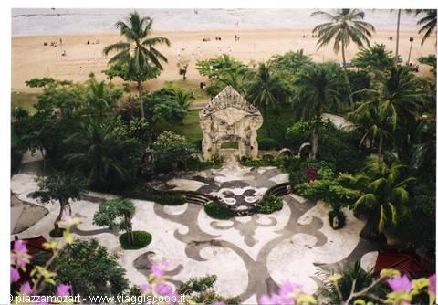 Carved stone gateway among palms and pool, Bali beach in the background