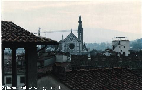 Basilica of Santa Croce in Florence among rooftops, façade and bell tower in haze