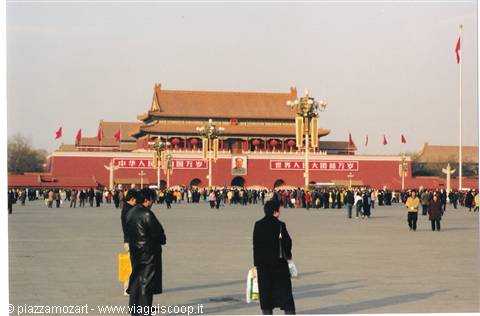 Tourists walk across Tiananmen Square in front of the Tiananmen Gate