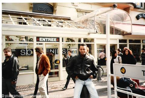 Man in leather jacket smiling in front of a café with glass entrance
