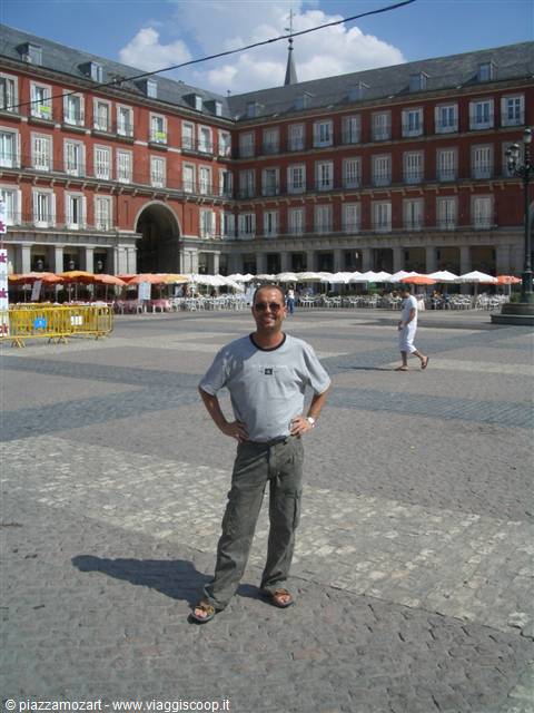 Smiling tourist standing in Madrid's Plaza Mayor, red buildings and café umbrellas