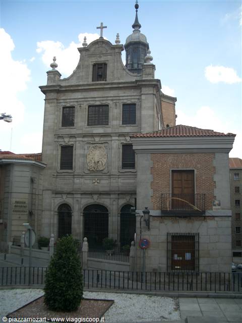 Gray stone church with cross and dome, blue sky with clouds