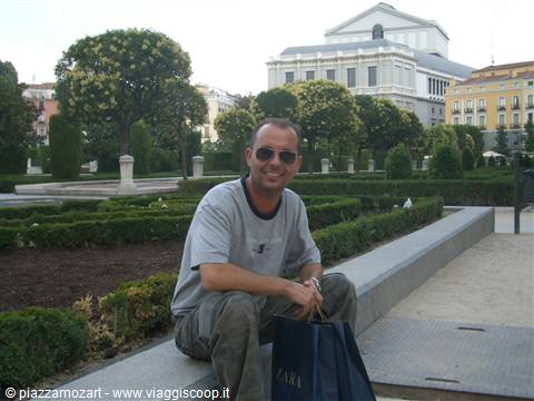 Smiling tourist with Zara bag sitting in Plaza de Oriente, Teatro Real behind