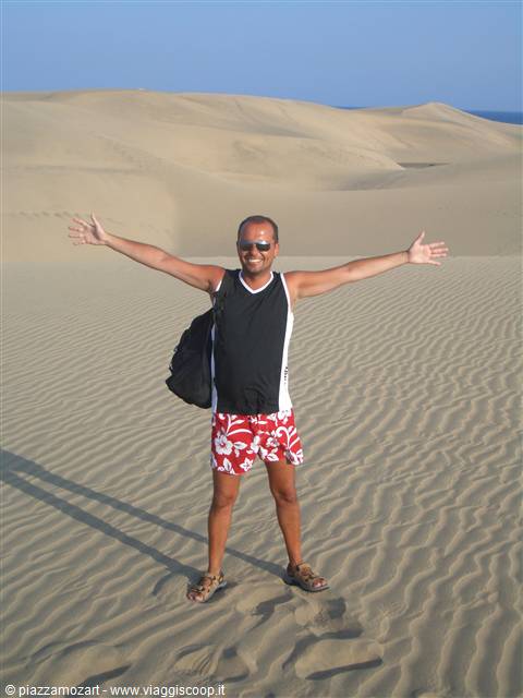 Man with backpack arms outstretched on the Maspalomas sand dunes