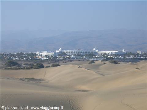 Maspalomas sand dunes with white buildings and mountains in the background