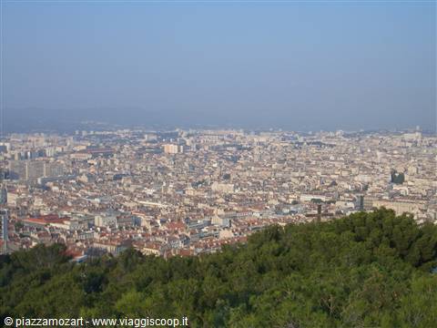 Marseille seen from above, pale rooftops stretching toward the hazy sea