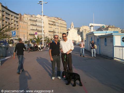 Two men with a black dog strolling along Marseille's Vieux-Port waterfront