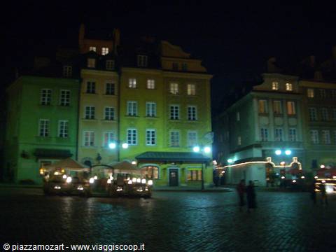 Square with colorful lit houses at night and wooden market stalls, Warsaw