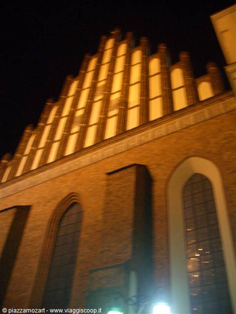 Gothic brick church facade lit at night with arched windows