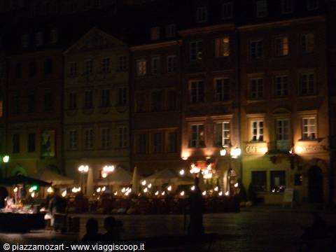 Café lights glow beneath historic old town facades at night