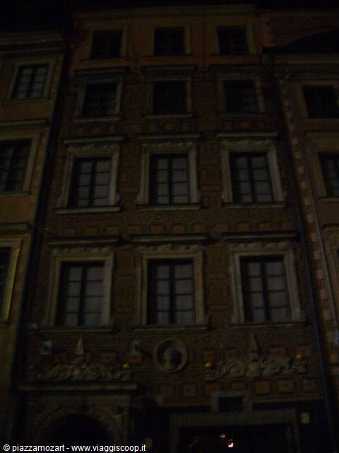Stucco facade of historic building with framed windows, faintly lit at night