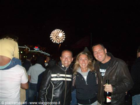 Three smiling friends in the night crowd, fireworks in the sky