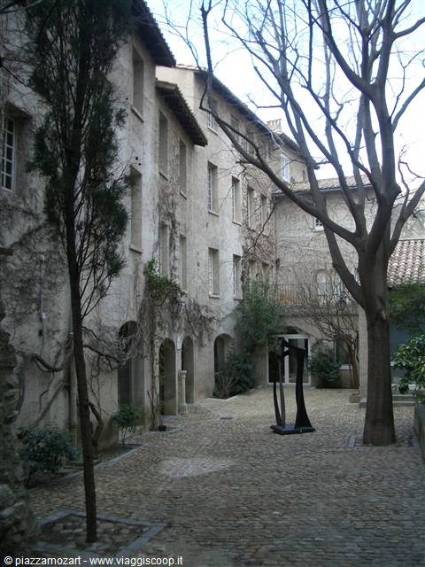 Cobblestone courtyard, old ivy-covered building, bare trees and black sculpture