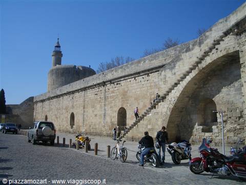 Motorcyclists resting under medieval stone ramparts and the Tour de Constance, Aigues-Mortes