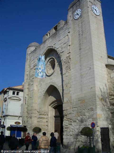 Tourists in front of the stone church facade, clock tower, clear blue sky