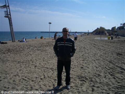 Man in jacket on the sand, diving platform, people on the beach