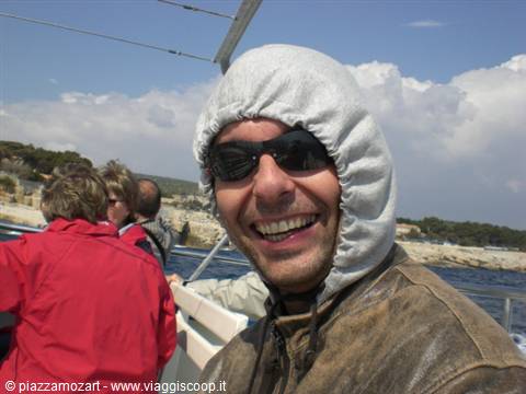 Man in hooded jacket and sunglasses smiling on a boat