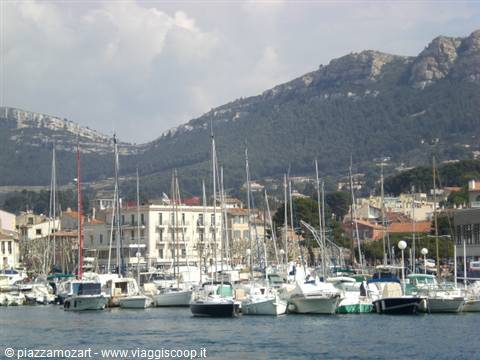 Sailboats moored in the harbor of Cassis, rocky hills behind