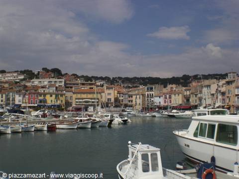 Fishing boats and yachts moored in Cassis harbour, colorful houses behind