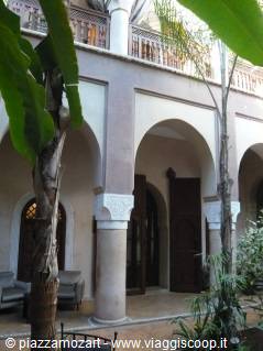 Courtyard of a riad with horseshoe arches, columns and palm trees