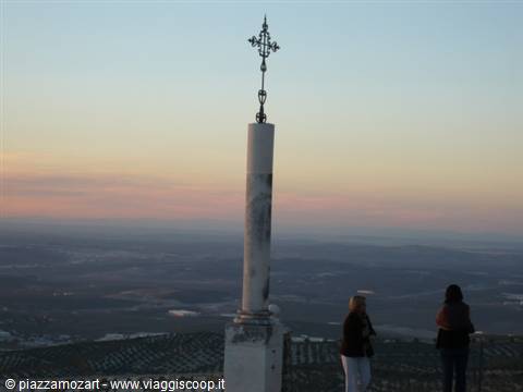 Two women beside a marble column topped with an iron cross