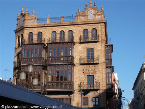 Brick building with wrought-iron balconies under a blue sky