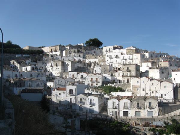 Whitewashed houses stacked on the hillside of Monte Sant'Angelo under blue sky