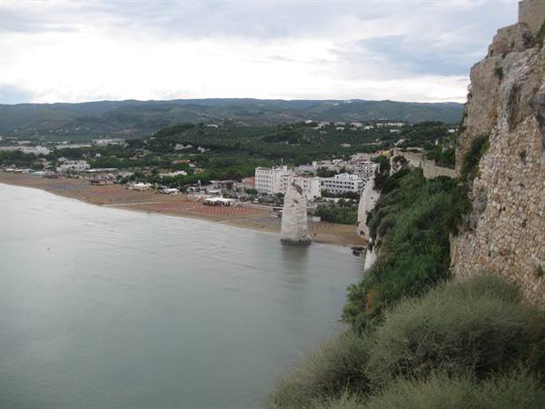 Pizzomucco sea stack by sandy beach and white town, Vieste