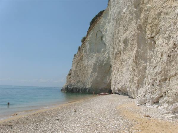 Pebble beach beneath white limestone cliffs, turquoise water, kayak ashore