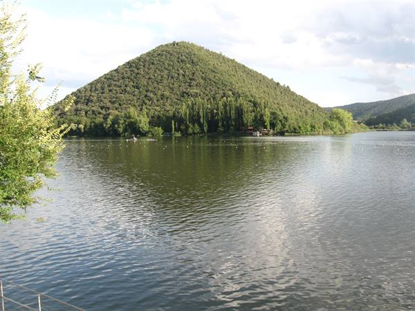 Wooded cone-shaped hill reflected in the calm lake, scattered clouds