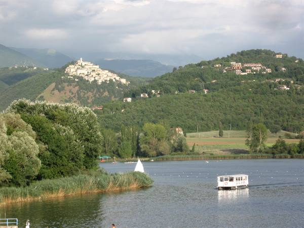 White ferry boat on Lake Piediluco, small sailboat near the tree-lined shore