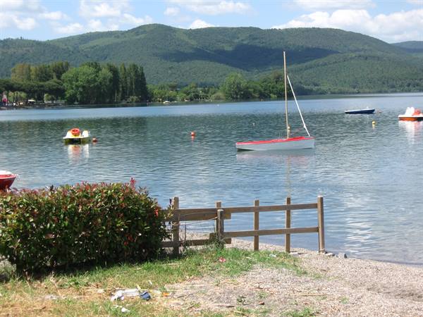 Red and white sailboat moored on the lake, wooden fence on the shore
