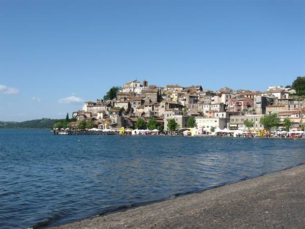 Anguillara Sabazia on Lake Bracciano, old stone houses rise above the beach umbrellas