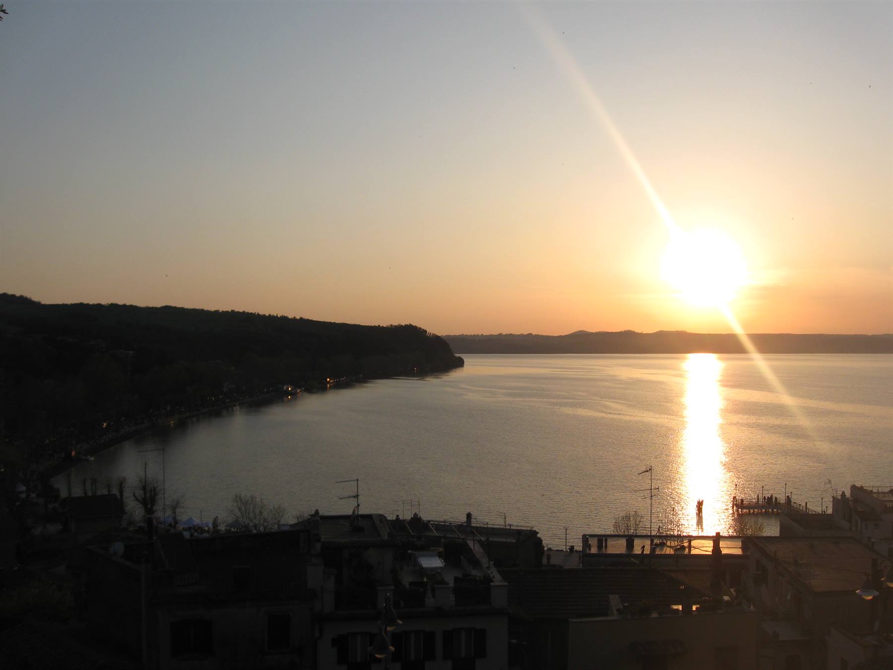 Sole basso sul lago di Bracciano, tetti e lungolago in controluce