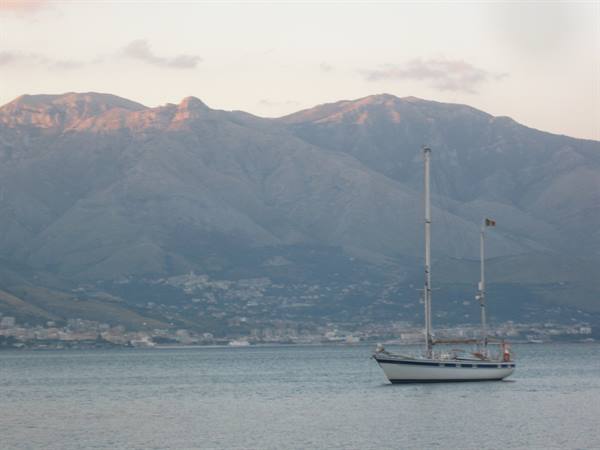 Sailboat anchored in front of the Sicilian mountains