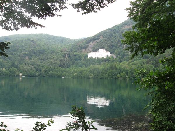 white building above the forest reflected in green Monticolo lake