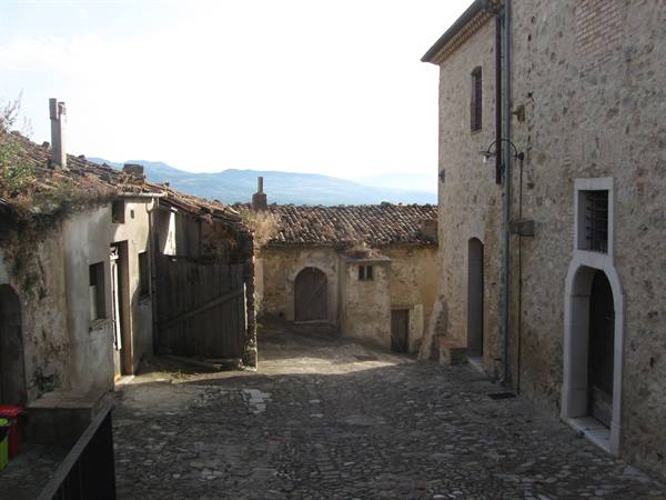 Stone alley of medieval village, old houses, hills in daylight