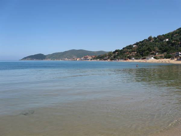 clear water and sandy shore by a village among green hills