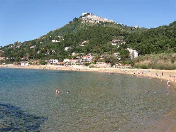 Swimmers in clear water beneath the hilltop village of Castellabate