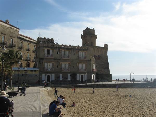 Tourists on the beach in front of the old village and tower of Santa Maria Castellabate