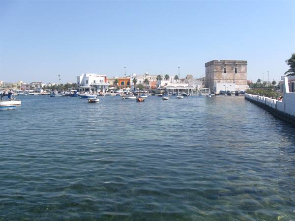 Boats in the harbor before Torre Vado, white houses and ancient stone tower