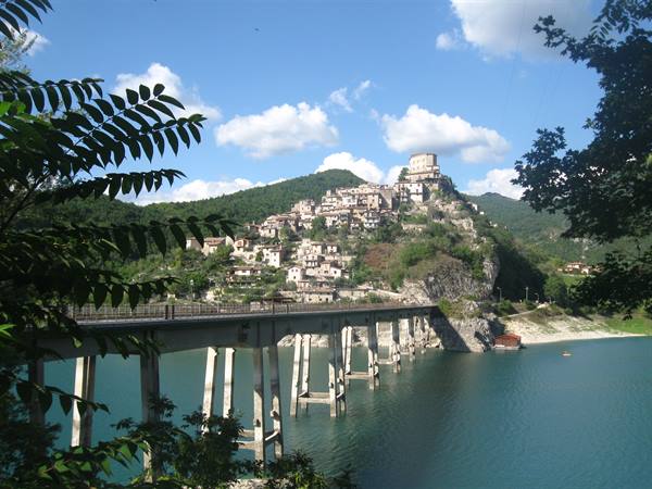 Concrete bridge over the turquoise lake in front of Castel di Tora village