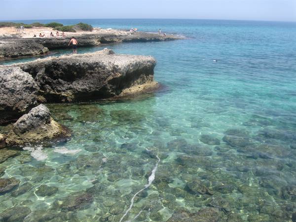 Limestone rocks with swimmers, clear turquoise sea on the Salento coast