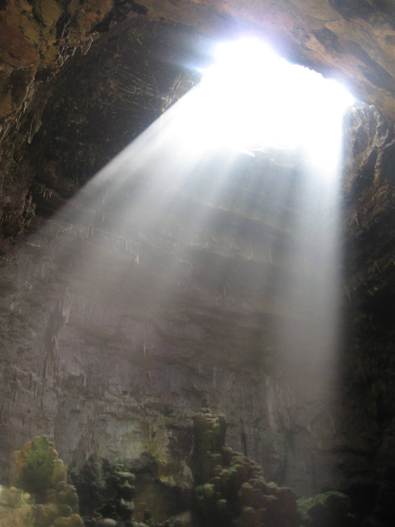Raggio di sole attraverso l'apertura della Grotta di Castellana, rocce calcaree e muschio