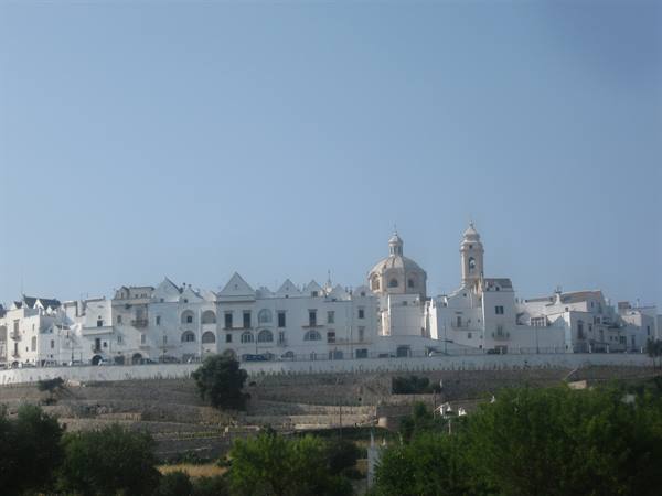 Ostuni, the white city: lime-whitened houses, dome and bell tower under blue sky