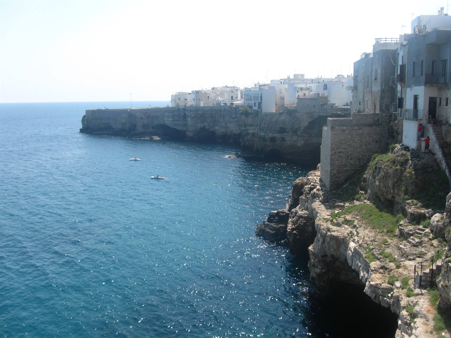 Case bianche su falesie calcaree a Polignano a Mare, barche sul mare azzurro