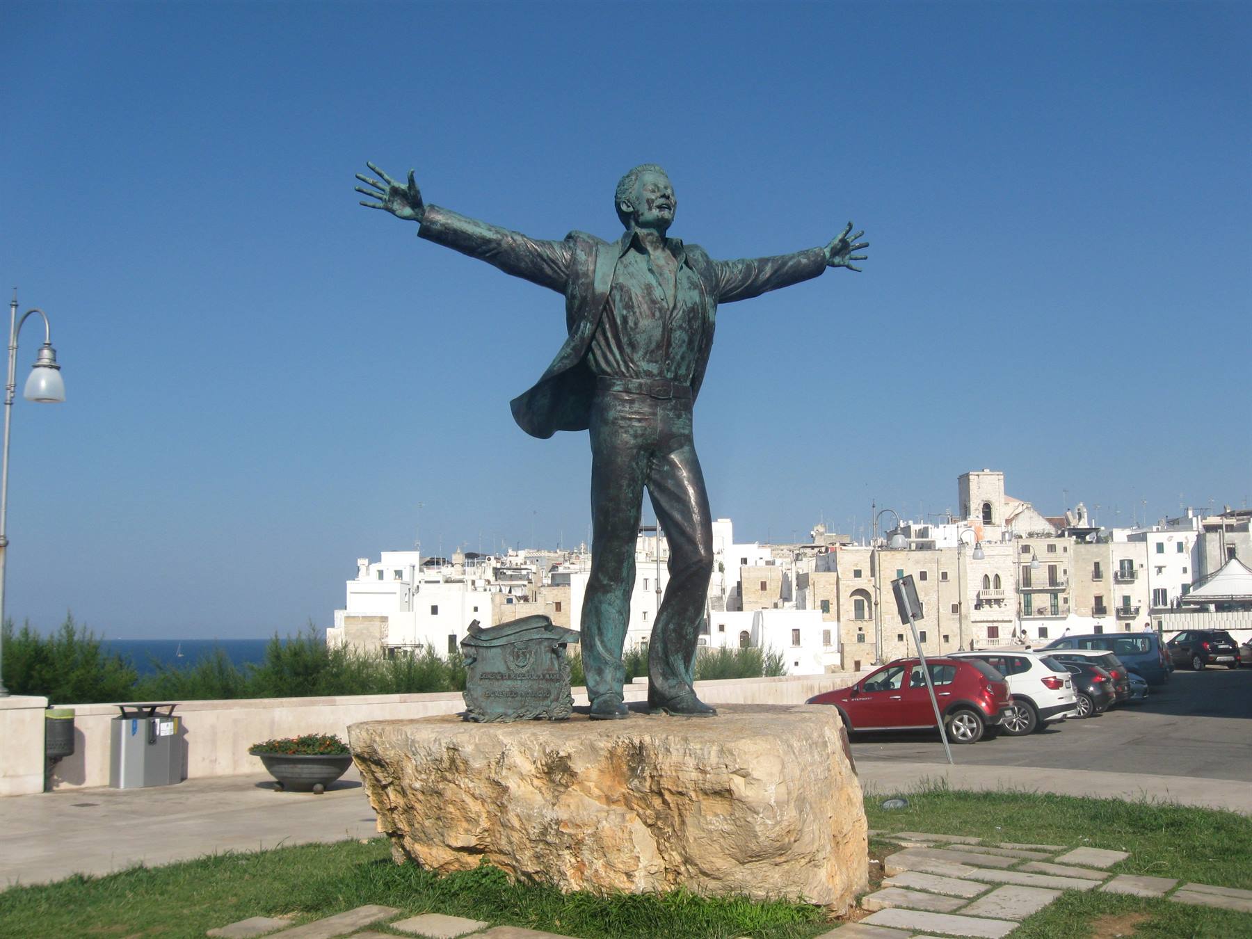 Statua in bronzo di Domenico Modugno con braccia aperte a Polignano a Mare