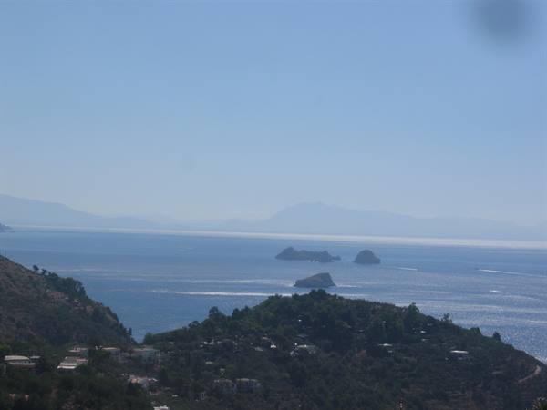 Li Galli islands on the blue sea, green coastal hills under clear sky