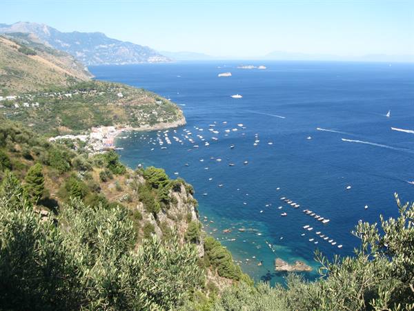 Dozens of anchored boats in the blue bay of the Amalfi Coast
