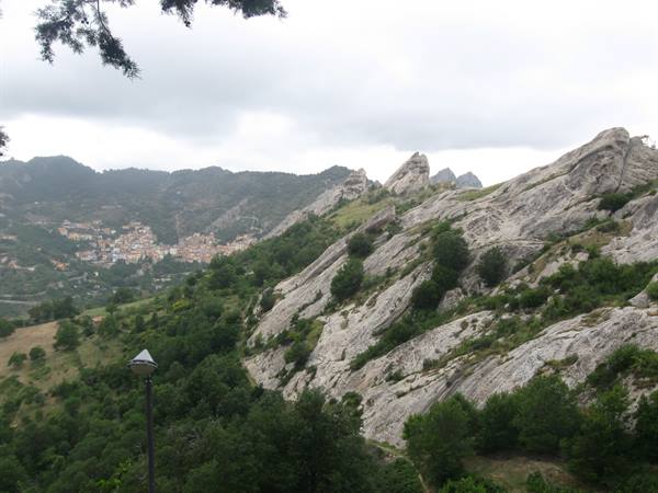 Granite rocks above a hillside village, cloudy sky, green vegetation below